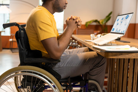 Man in wheelchair working on laptop with migration analytics dashboard