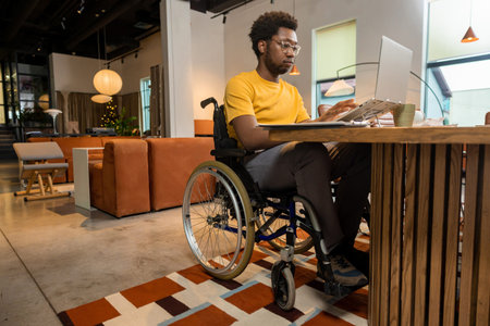 African American man in wheelchair concentrating on laptop