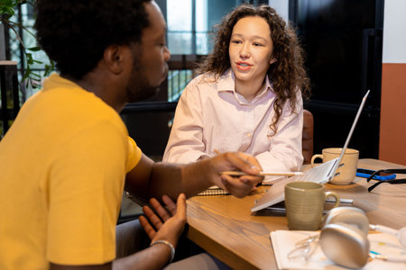 Man and woman colleagues discussing project using computer in coworking space