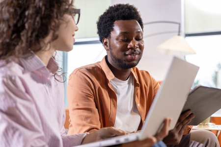 Man with laptop talking with colleague in coworking workspace