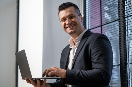 Male professional typing on laptop and smiling during work session