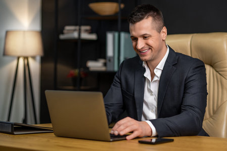Confident male executive working on laptop and smiling in office environment