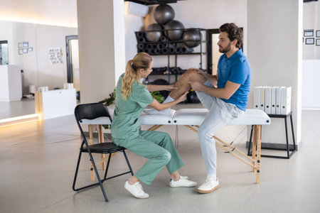 Female doctor checking patient leg during physiotherapy