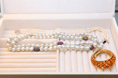 Lots of bracelets and pearl jewelry with diamonds and other stones in the jewelry boxの写真素材