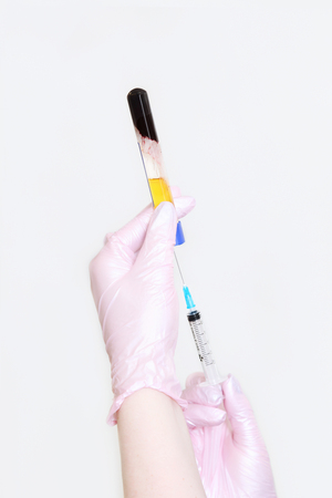 Test tube in his hands with blood plasma and syringe in his hand for injection.の写真素材