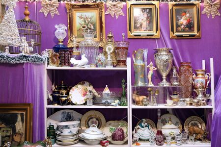 Huge shelving shelves with different vintage beautiful dishes made of porcelain and glass, plates, vases, figurines at the flea market. Moscow. 12.12.2018の写真素材