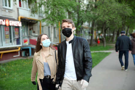 Young girl and a guy in masks holding hands in gloves on the street. Moscow.11.05.2020のeditorial素材
