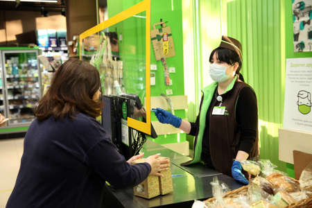 Woman buys food at a store and a cashier with gloves and a mask on his face. Moscow.11.05.2020