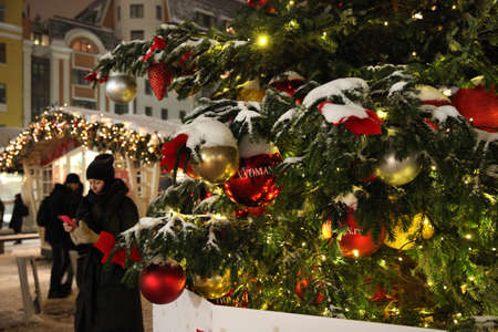 Girls with a phone near a large Christmas tree at the new year's city fair in the evening. Moscow. 24.12.2018のeditorial素材