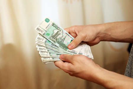 Bundle of money, banknotes with a face value of 1000 rubles in the hands of a young man. Moscow....