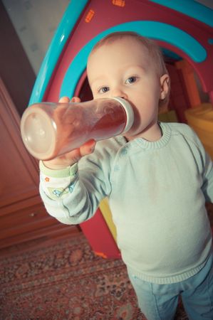 Young baby boy with bottle of juiceの写真素材