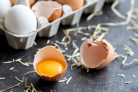 Fresh organic raw eggs, white, beige and brown, one is cracked