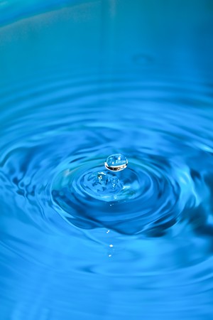 Clean blue drop of water splashing in clear water. Abstract blue backgroundの写真素材