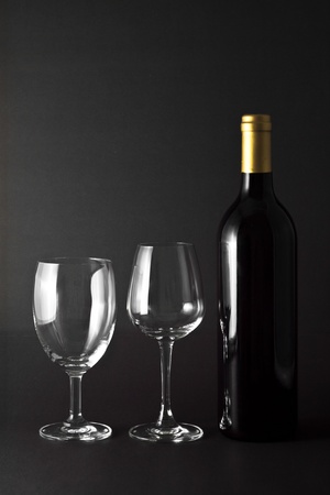 A bottle of red wine and two elegant glasses on black backgroundの写真素材
