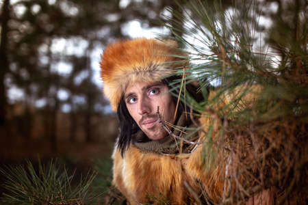 Image of a young man in a fox fur hat in the forest