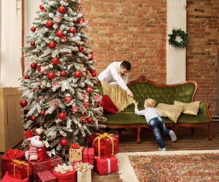 Image of dad playing with his little son in a room with a christmas treeの写真素材