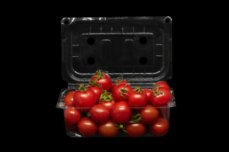 Image of small tomatoes in plastic packaging on a black backgroundの写真素材