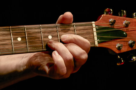 Image of a musician's fingers playing a chord on a guitar neck