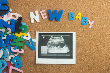 Colourful word new baby and ultrasound results with cork board as backgroundの写真素材