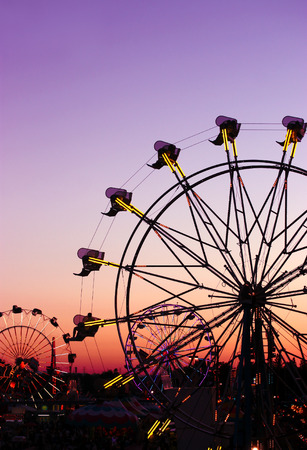Silhouettes of carnival rides under sunsetの写真素材