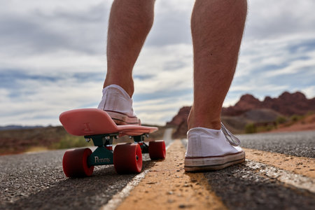 Close-up of a man riding a longboard on the roadの写真素材