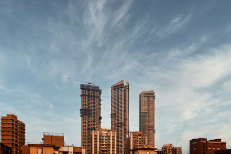 High rise buildings under construction with blue sky and white clouds background.