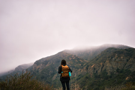 woman hiker enjoy the view on top of mountain at foggy day