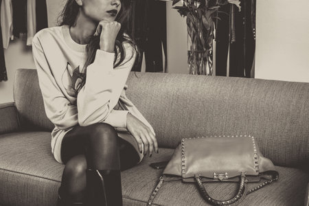 Young woman sitting on sofa with handbag. Black and white.の写真素材