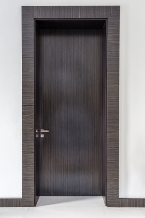 Wooden door in a room with white wall and tiled floorの写真素材