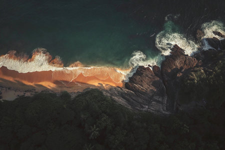 Aerial view of the ocean waves crashing on the rocks at sunsetの写真素材