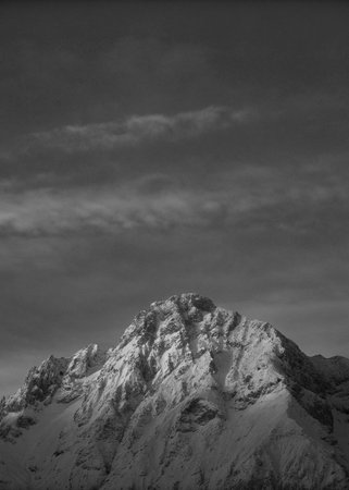 Black and white image of a snowy mountain peak in the clouds.の写真素材