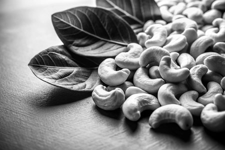 Cashew nuts with leaves on wooden table. Black and white.