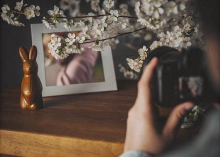 Female photographer taking picture of easter bunny with easter eggs and flowersの写真素材