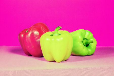 Three colorful bell peppers on pink background. Selective focus. Toned.の写真素材