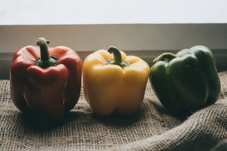 Three bell peppers on sackcloth background. Selective focus. Toned.