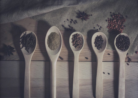 Spices in wooden spoons on wooden background. Vintage tone.の写真素材