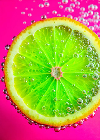 Slices of lime in water with bubbles on a pink background