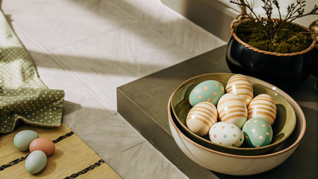 Easter eggs painted in pastel colors in a ceramic bowl on the tableの素材