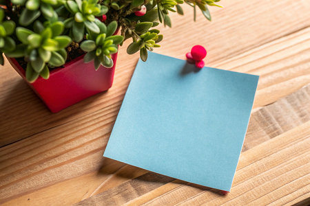 Blank note paper with green plant on wooden table, stock photoの素材