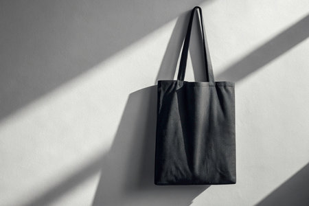 mockup Black cotton bag on white wall with shadow overlay. Mockup for designの素材