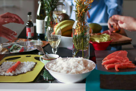 Homemade salmon and rice sushi preparation with friendの写真素材