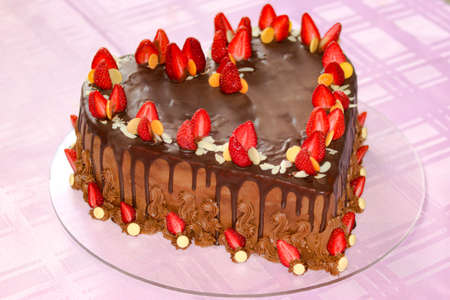 Heart-shaped chocolate cake with strawberries on the top with the pink backgroundの写真素材