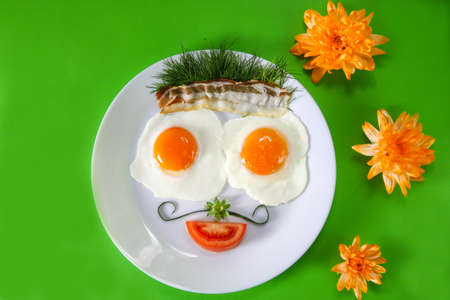 smiling english breakfast face with eggs and bacon with green backgroundの写真素材