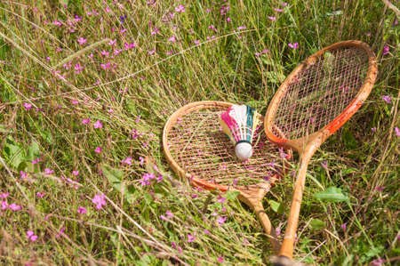 Two wooden badminton rackets and a shuttlecock lie on the meadow grassの写真素材