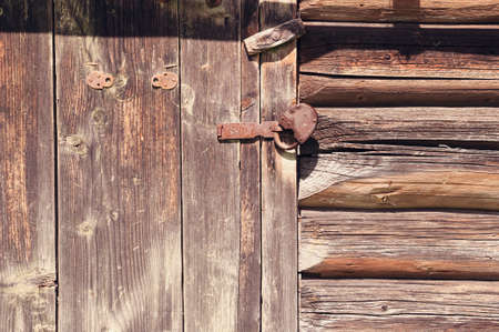 Texture of old logs and door on the wall of a rustic wooden buildingの写真素材