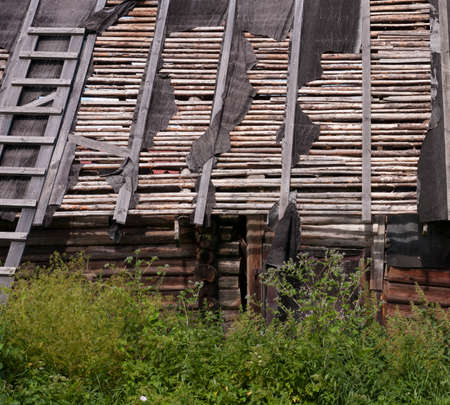 Old broken wooden roof of rural building with logs and planksの写真素材