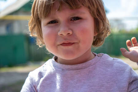Little three years old boy outdoors portrait. Cute boy with long curly hair look in camera close upの写真素材