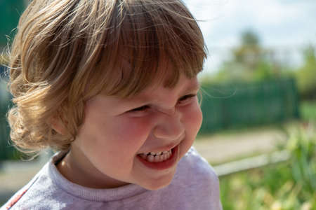 Little three years old boy outdoors portrait. Cute boy make angry face with teeth close upの写真素材