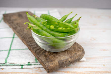 raw green pea in a glass bowl on wooden boardの写真素材