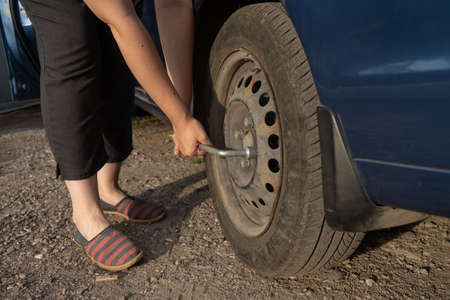 woman tighten the bolts on a disk, changing tire manually, car wheelの写真素材